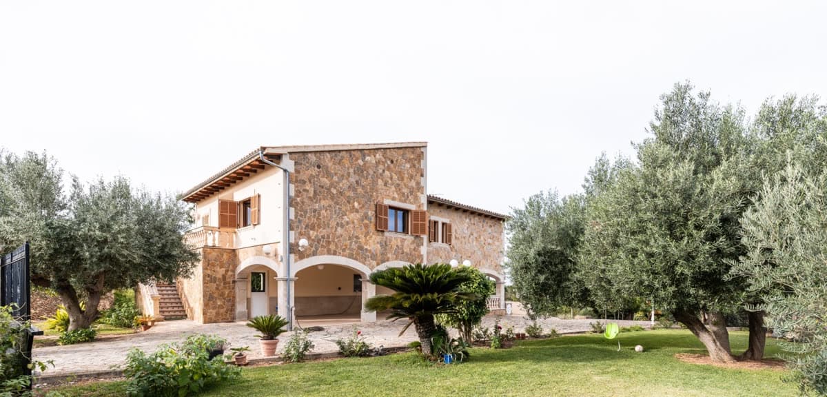 Stone house surrounded by olive trees and a garden