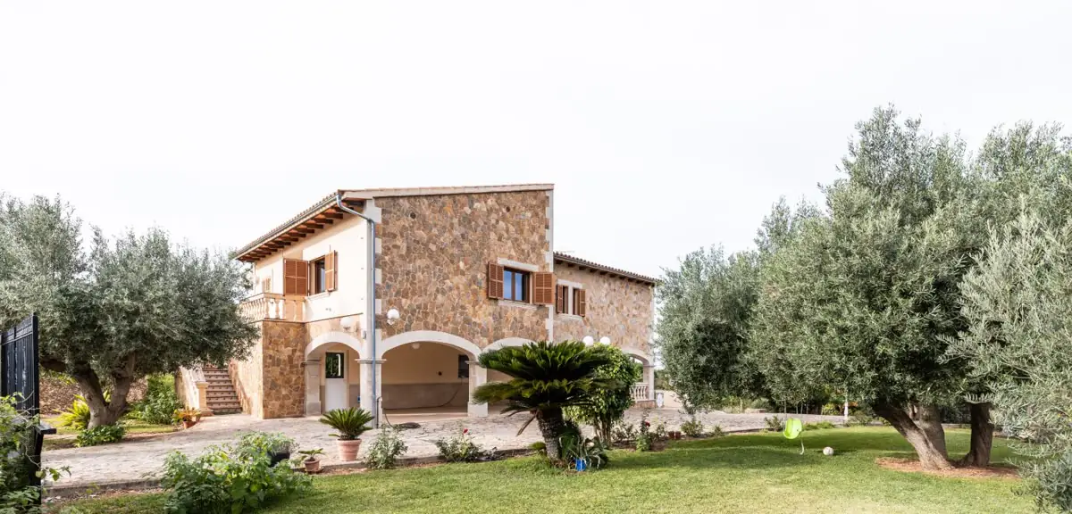 Xalet de pedra envoltat d’oliveres i jardí